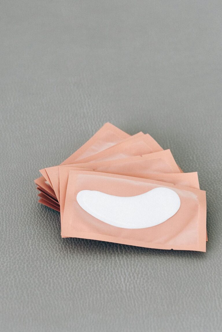 Close-up of brown packets containing white eye patches on a textured gray surface.
