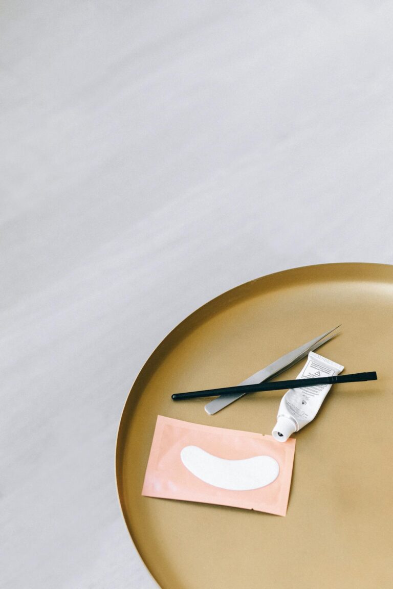 Minimalist flat lay of skincare tools and eye mask on round golden tray, ideal for beauty and wellness concepts.